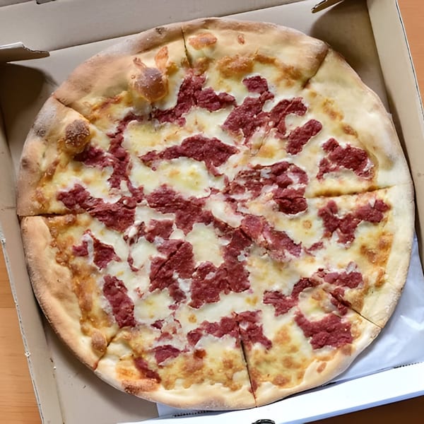 Greco's Pizzeria's corned beef pizza, with white cheese and red meat, in a cardboard box.